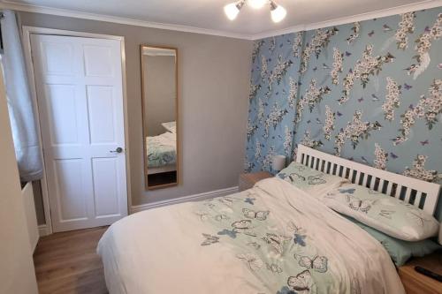 a bedroom with a bed with a floral wallpaper at 'rose cottage' a 19th century cottage in Findern in Findern