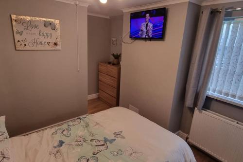 a bedroom with a bed and a tv on the wall at 'rose cottage' a 19th century cottage in Findern in Findern