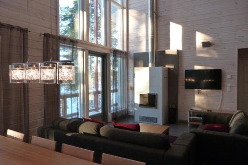 a living room with couches and a tv andwindows at Tallusniemi Villas in Oravi