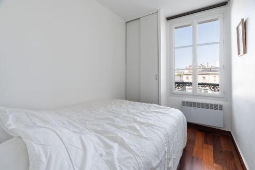 une chambre blanche avec un lit et une fenêtre dans l'établissement A cosy 1-BDR in Montparnasse, à Paris