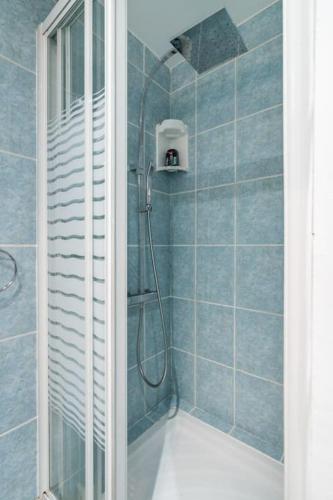 une salle de bain avec douche aux carreaux bleus dans l'établissement A cosy 1-BDR in Montparnasse, à Paris