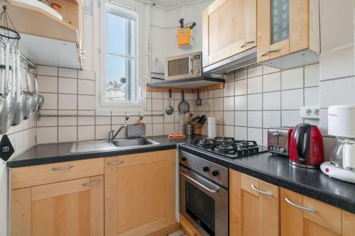 une cuisine avec des armoires en bois et un four à plaques de cuisson dans l'établissement A cosy 1-BDR in Montparnasse, à Paris