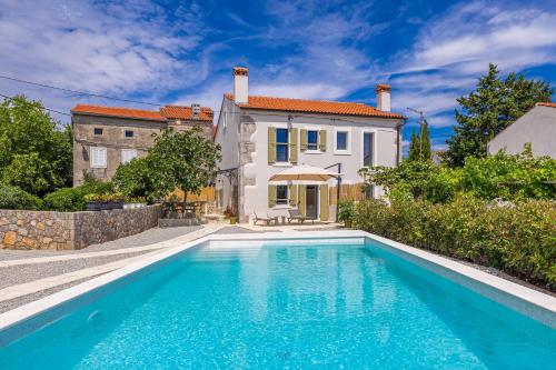 a villa with a swimming pool in front of a house at Holiday house Rural home Frane in Kornić