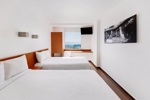 a hotel room with two beds and a window at One Cuernavaca in Cuernavaca