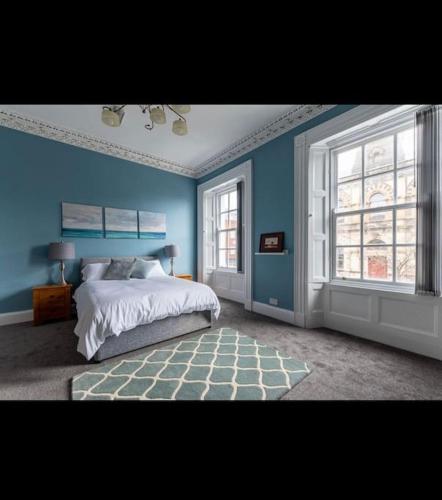 a blue bedroom with a bed and two windows at 4bed Townhouse in heart of Sligo in Sligo