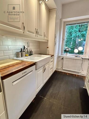 a kitchen with white cabinets and a sink and a window at C Apartments Annedal in Gothenburg
