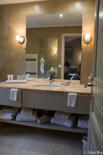 une salle de bain avec un lavabo et un grand miroir dans l'établissement Domaine de Mejeans - Teritoria, à Alleins
