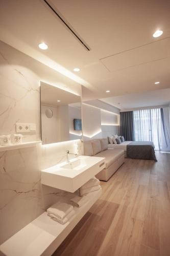a white bathroom with a sink and a couch at Hotel Montemar Maritim in Santa Susanna