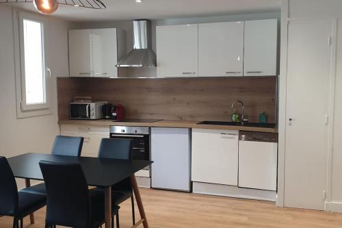 une cuisine avec des armoires blanches et une table et des chaises dans l'établissement R'Apparts T2 Duplex Urbain, à Grenoble