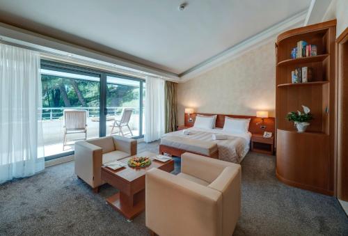 a hotel room with a bed and a table and chairs at Monte Casa SPA & Wellness in Petrovac na Moru