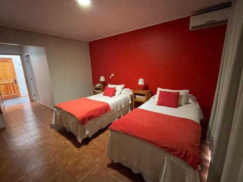 two beds in a hotel room with red walls at Hotel Altos de Tuqui in Ovalle