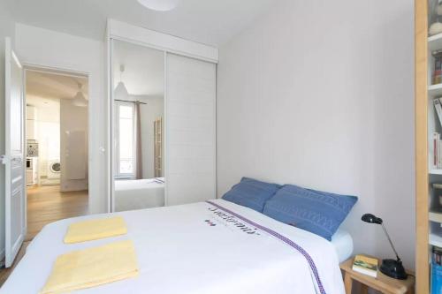 a white bed with blue pillows in a bedroom at Beautiful Large Flat, 15min from Paris center in Gentilly