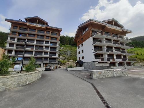 un grand immeuble situé à côté d'un parking dans l'établissement Studio skis aux pieds proche centre, balcon, parking, animaux admis - FR-1-514-33, à Courchevel
