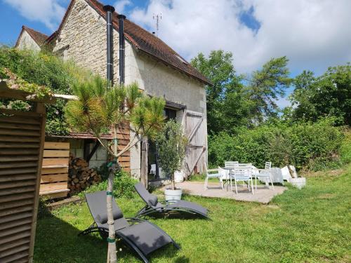 un jardin avec des chaises et une table ainsi qu'une maison dans l'établissement La Grange du Moulin, à Noyers-sur-Cher