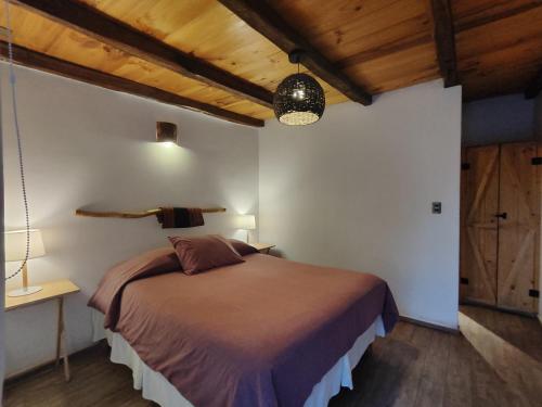 una camera con letto in una stanza con soffitti in legno di Hostal Lackuntur a San Pedro de Atacama