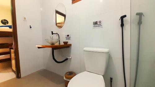 a bathroom with a toilet with a mirror and a sink at Pousada do Rock in Arraial d'Ajuda
