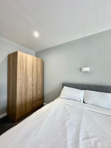 a bedroom with a bed and a wooden cabinet at Ashiana in Newark upon Trent