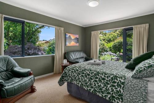a bedroom with a bed and a chair and windows at Tropical Avocado Orchard Escape Ohauiti in Ohauiti