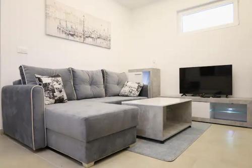 sala de estar con sofá gris y TV de pantalla plana en Apartments R&M, en Tivat