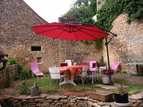 une table et des chaises avec un parasol rouge dans l'établissement Gîtes dans village médiéval Périgord, à Limeuil