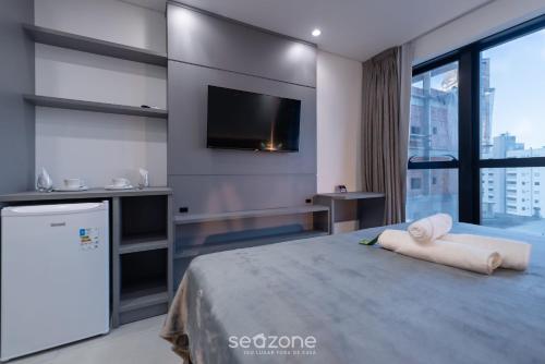 a bedroom with a large bed with a flat screen tv at MHFA - Studios em Prédio Luxuoso com Vista Mar in Itapema