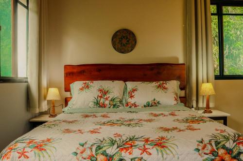 a bedroom with a bed with a floral bedspread at Tapovan in São Bento do Sapucaí
