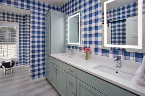 a blue tiled bathroom with two sinks and two mirrors at The Inn at Stonecliffe in Mackinac Island