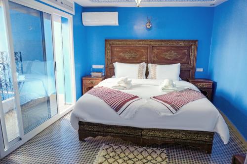 - une chambre avec un grand lit aux murs bleus dans l'établissement RIAD CHENGLI 蓝城里, à Chefchaouen