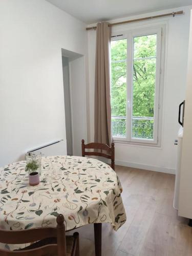 une salle à manger avec une table et une fenêtre dans l'établissement Bel Appartement avec vue square - Paris Nation - 3 Voyageurs, à Paris