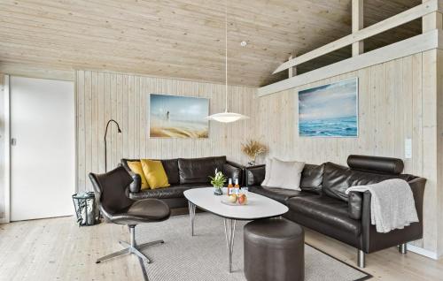 a living room with a black leather couch and a table at Holiday Home Monasvej Løkken Iv in Grønhøj
