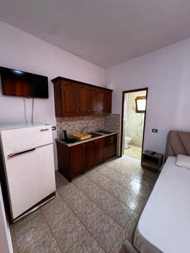 a kitchen with a white refrigerator and wooden cabinets at Villa Shpetim Zogaj. in Ksamil