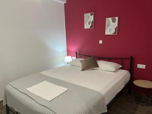 ein Schlafzimmer mit einem weißen Bett mit einer roten Wand in der Unterkunft Ammos & Thalassa Apartments in Ofrynio