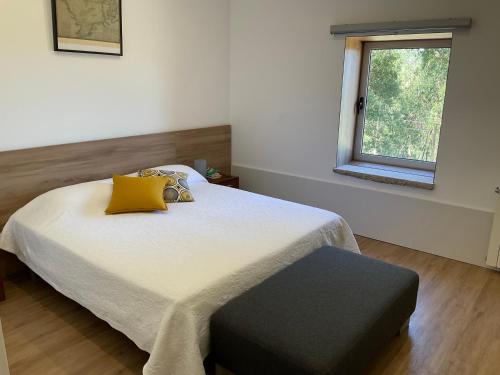 a bedroom with a bed with yellow pillows and a window at Cantinho do Carmo in Fragoso