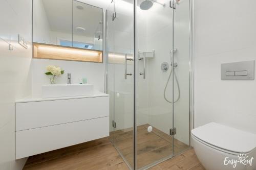 a bathroom with a glass shower and a sink at Apartamenty Pinea z widokiem na morze Easy - Rent Apartments in Pobierowo