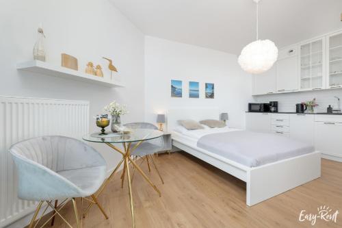 a white bedroom with a bed and a table at Apartamenty Pinea z widokiem na morze Easy - Rent Apartments in Pobierowo