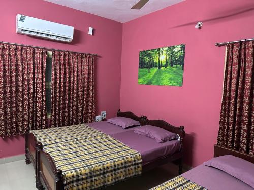 a bedroom with two beds and a pink wall at Chidambaram Spiritual Stay in Chidambaram