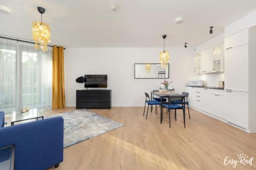 a living room with a table and chairs and a kitchen at Apartamenty Pinea z widokiem na morze Easy - Rent Apartments in Pobierowo