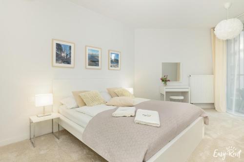 a white bedroom with a bed in a room at Apartamenty Pinea z widokiem na morze Easy - Rent Apartments in Pobierowo