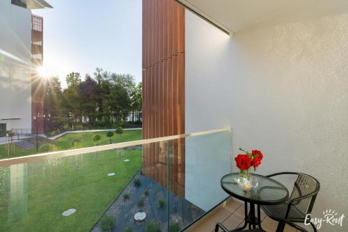 a balcony with a table and a view of a yard at Apartamenty Pinea z widokiem na morze Easy - Rent Apartments in Pobierowo