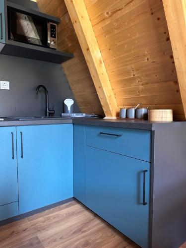 a kitchen with blue cabinets and a wooden ceiling at Oasis of peace in Šavnik