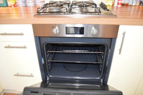 a stove with an open oven in a kitchen at Entire Apartment next to Canary Wharf in London in London