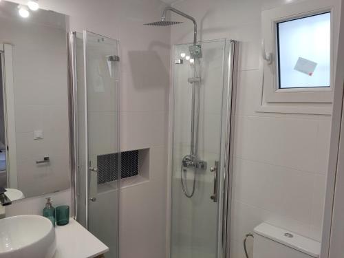 a white bathroom with a shower and a sink at Casa Laida in Sanlúcar de Barrameda