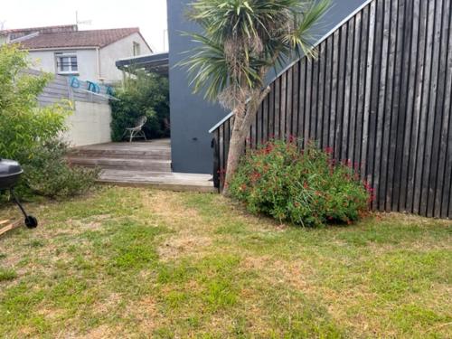 une maison avec une clôture et un palmier dans une cour dans l'établissement Charmante maison de vacances, à Saint-Michel-Chef-Chef