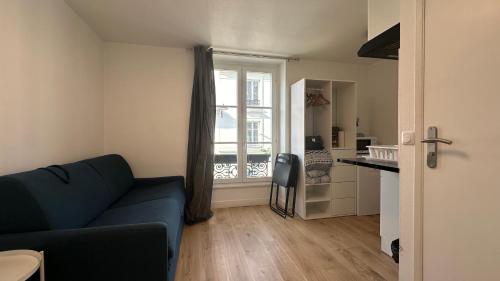 un salon avec un canapé bleu et une cuisine dans l'établissement Le Chic Urbain, à Paris