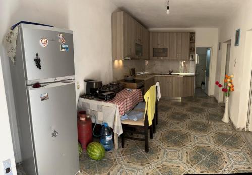 a kitchen with a refrigerator and a table in it at Private house surrounded by greenery in Fier