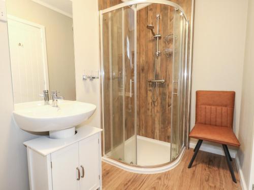 y baño con ducha, lavabo y silla. en Hazelwood 2, en Lyme Regis