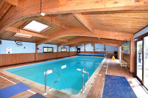 a large indoor pool with a wooden ceiling at Hazelwood 2 Pinewood Retreat in Lyme Regis