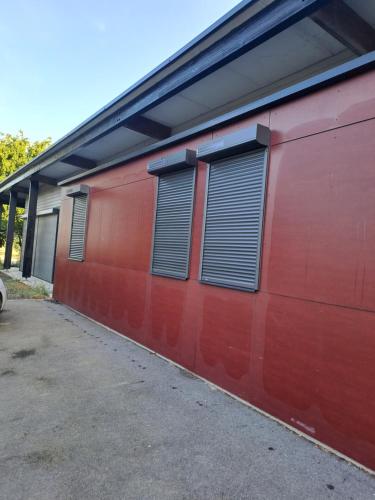 un bâtiment rouge avec deux fenêtres sur son côté dans l'établissement Maison en campagne, à Meillac