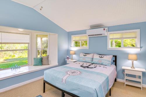 a blue bedroom with a bed and two windows at Bayfront Steuben Home with Screened Porch and Fire Pit in Steuben