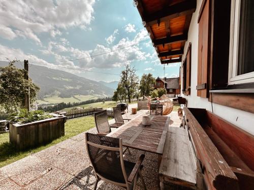 einen Holztisch und Stühle auf einer Veranda mit Aussicht in der Unterkunft CHILLHAUS Pear Mountain in Birnberg